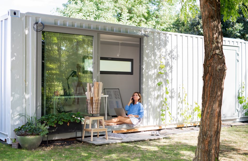 Mature woman working in home office in container house in backyard - Yellowhead storage